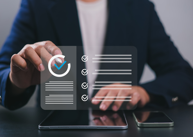 Person im Anzug, die eine virtuelle Checkliste abhakt - auf dem Tisch sind ein Smartphone und ein Tablet.